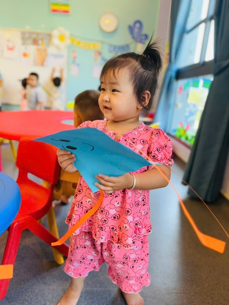 Bé gái cầm diều giấy tự làm trong lớp — Mầm non Nhân Lễ