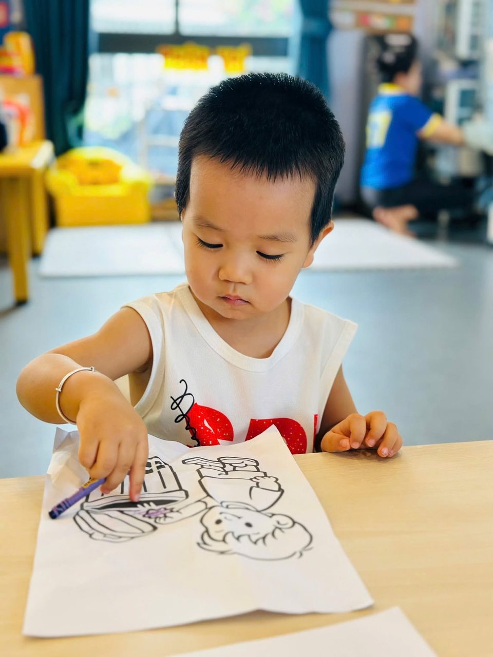 Bé trai tập trung tô màu tại bàn học — Mầm Non Việt Anh