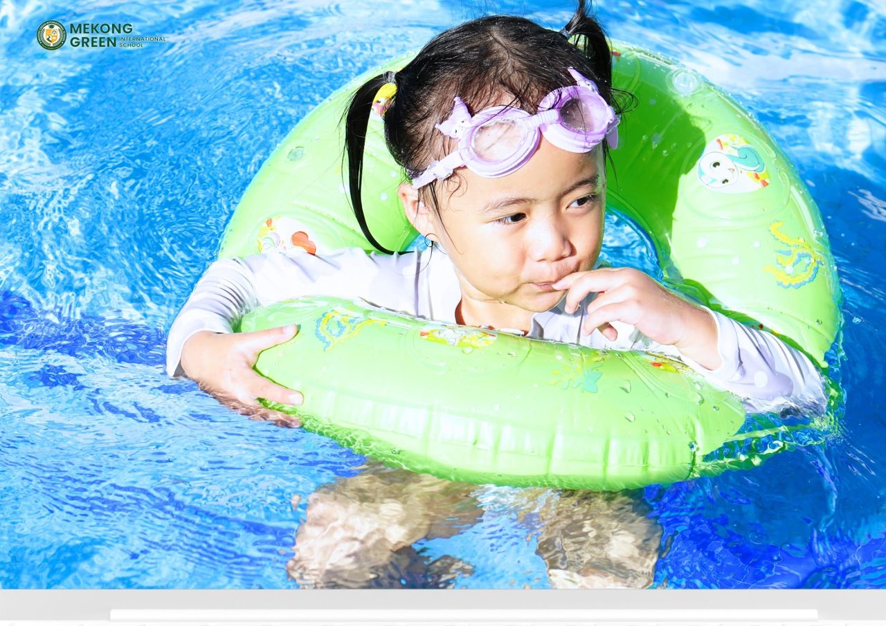 Bé gái đeo kính bơi với phao trong hồ bơi — Mekong Green
