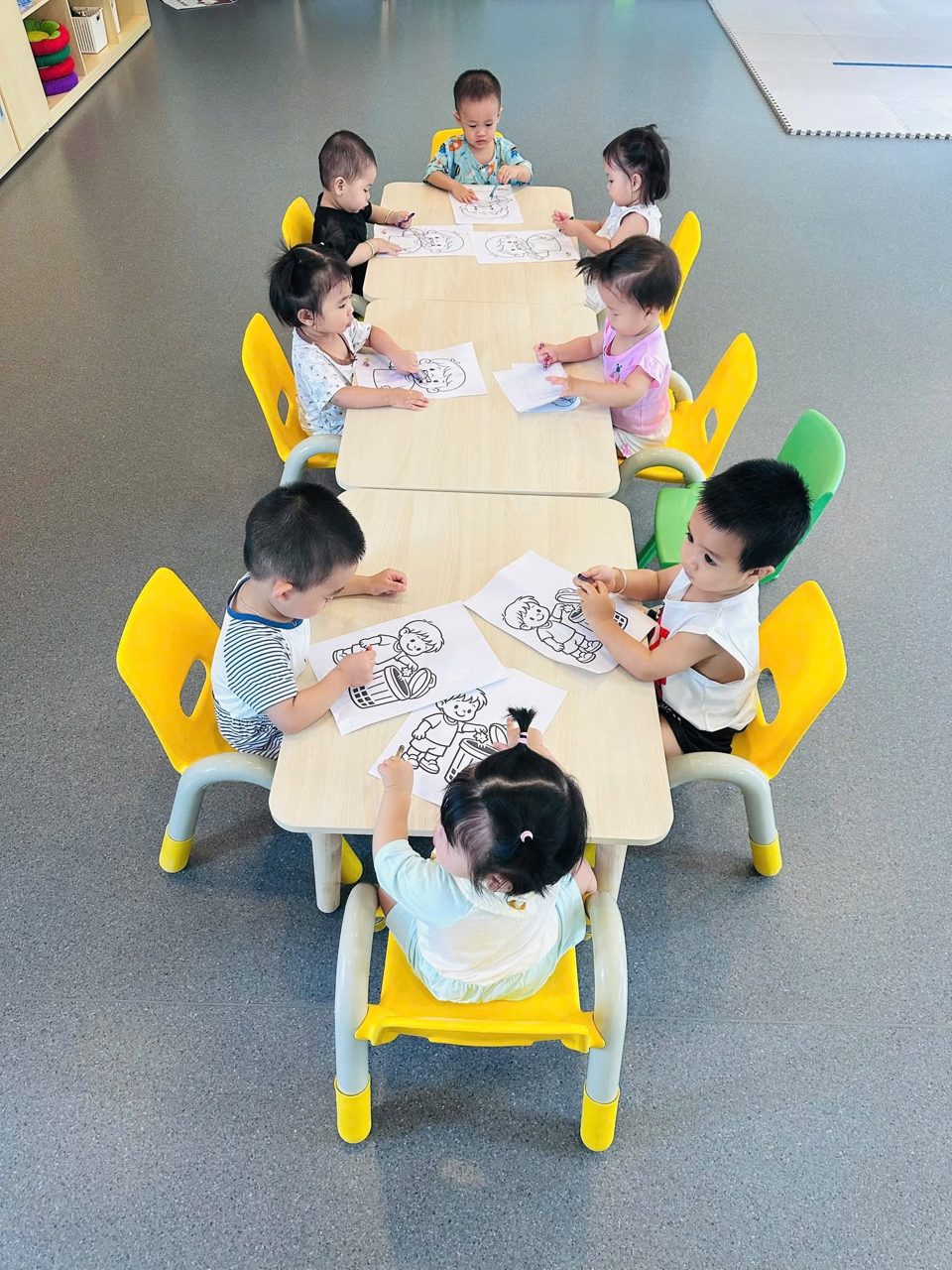 Các bé ngồi bàn nhóm tô màu trong giờ tạo hình — Mầm Non Việt Anh